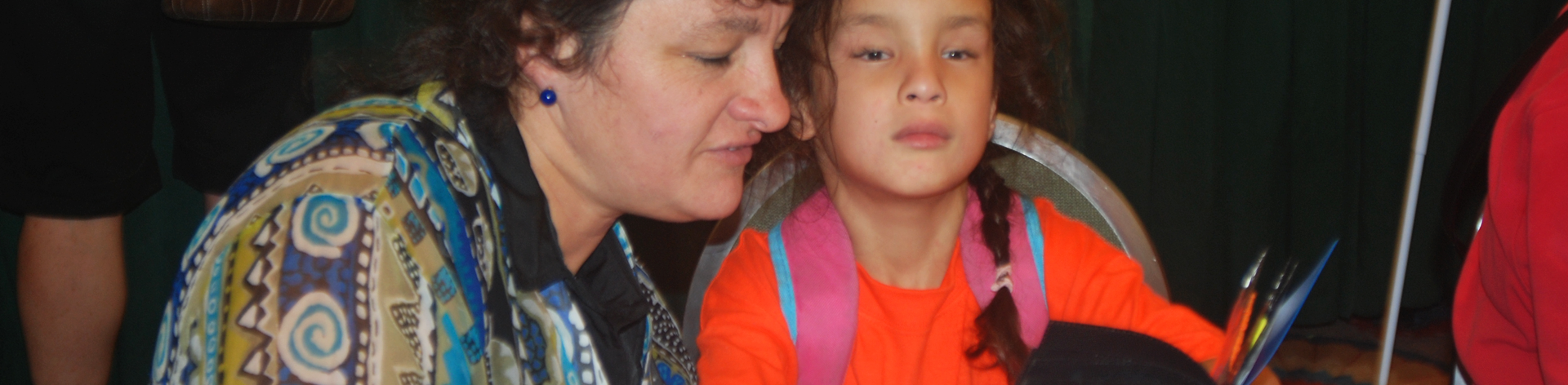 A mom reads a book to her blind daughter.